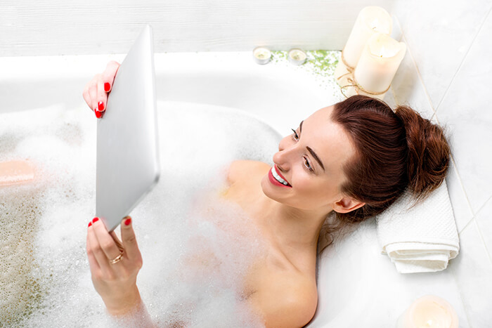 Junge Frau in Badewanne mit Tablet